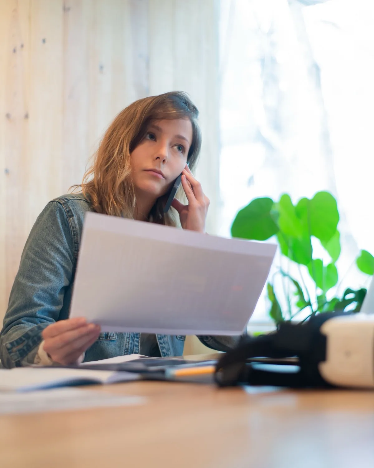 Eine Person prüft während eines Telefonats konzentriert Unterlagen.